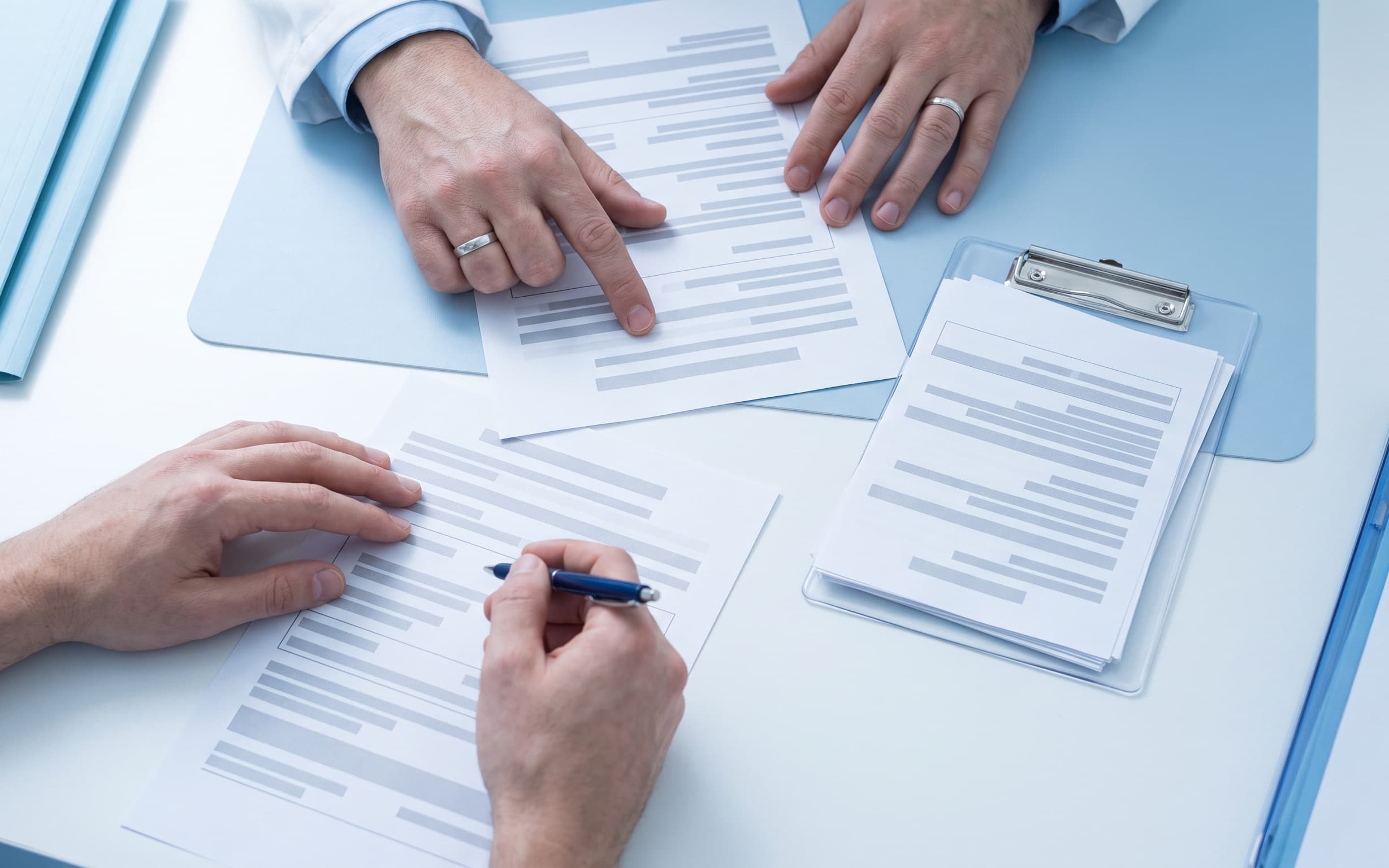 Hands reviewing clinical study documents on a clinic table